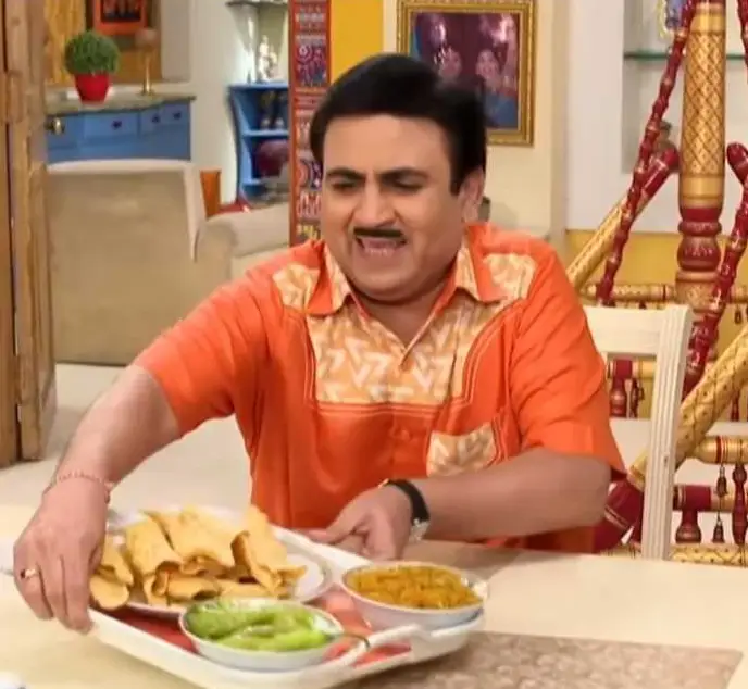 Jethalal eagerly pulls a plate of Fafda jalebi towards himself, accompanied by a green chilli