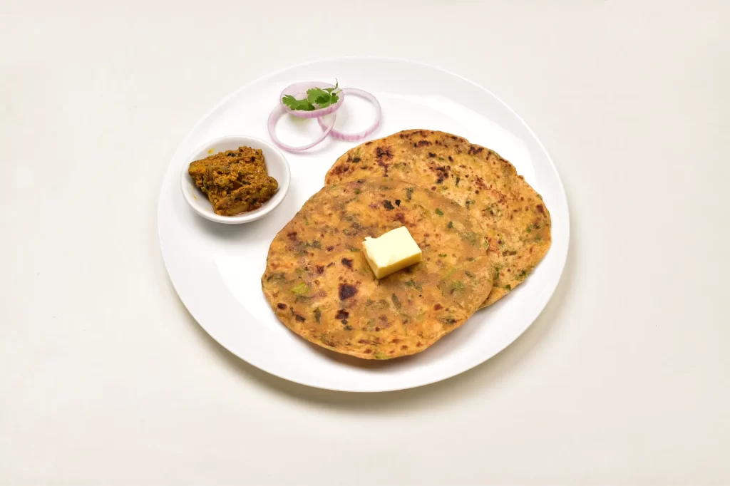 Gujarati Thepla served with tangy pickle on a white plate