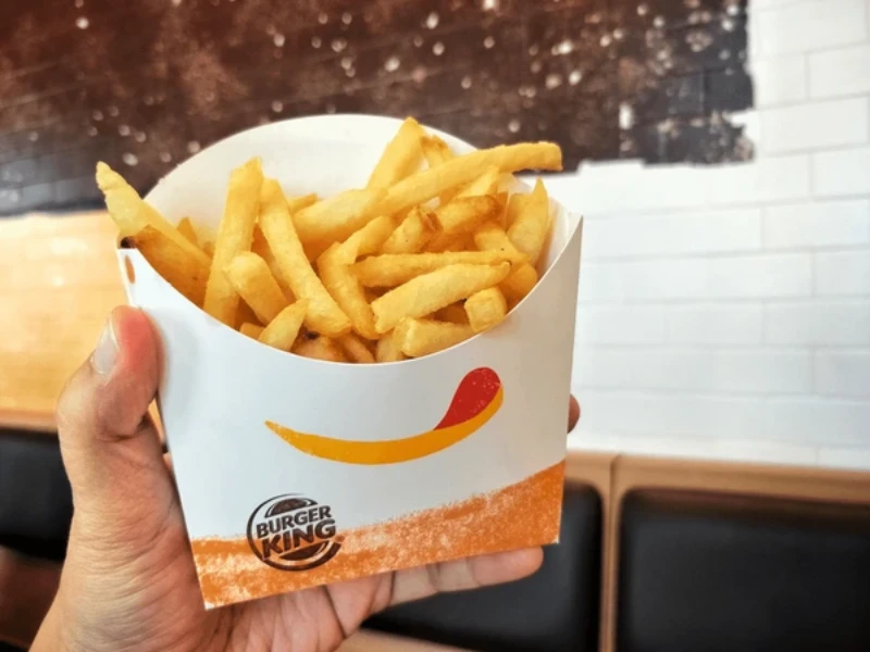 a hand holding a pack of Burger King fries